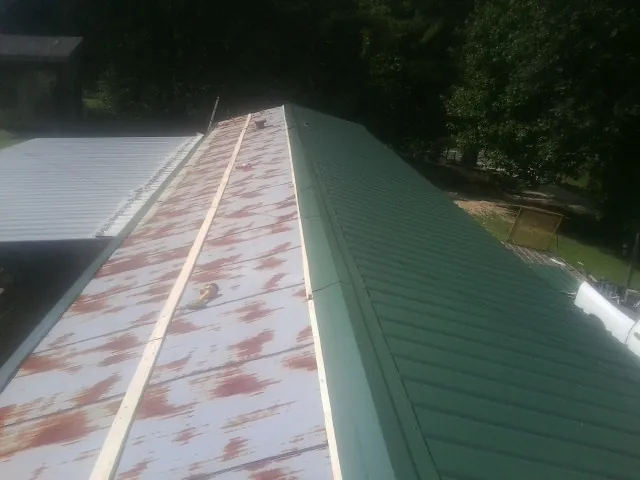 Old rusted panels beside newly installed green metal roofing — Wind Damage Roof Repair by Roofing Brothers in Belleair Beach